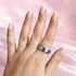 Hand wearing a silver ring on a pink background
