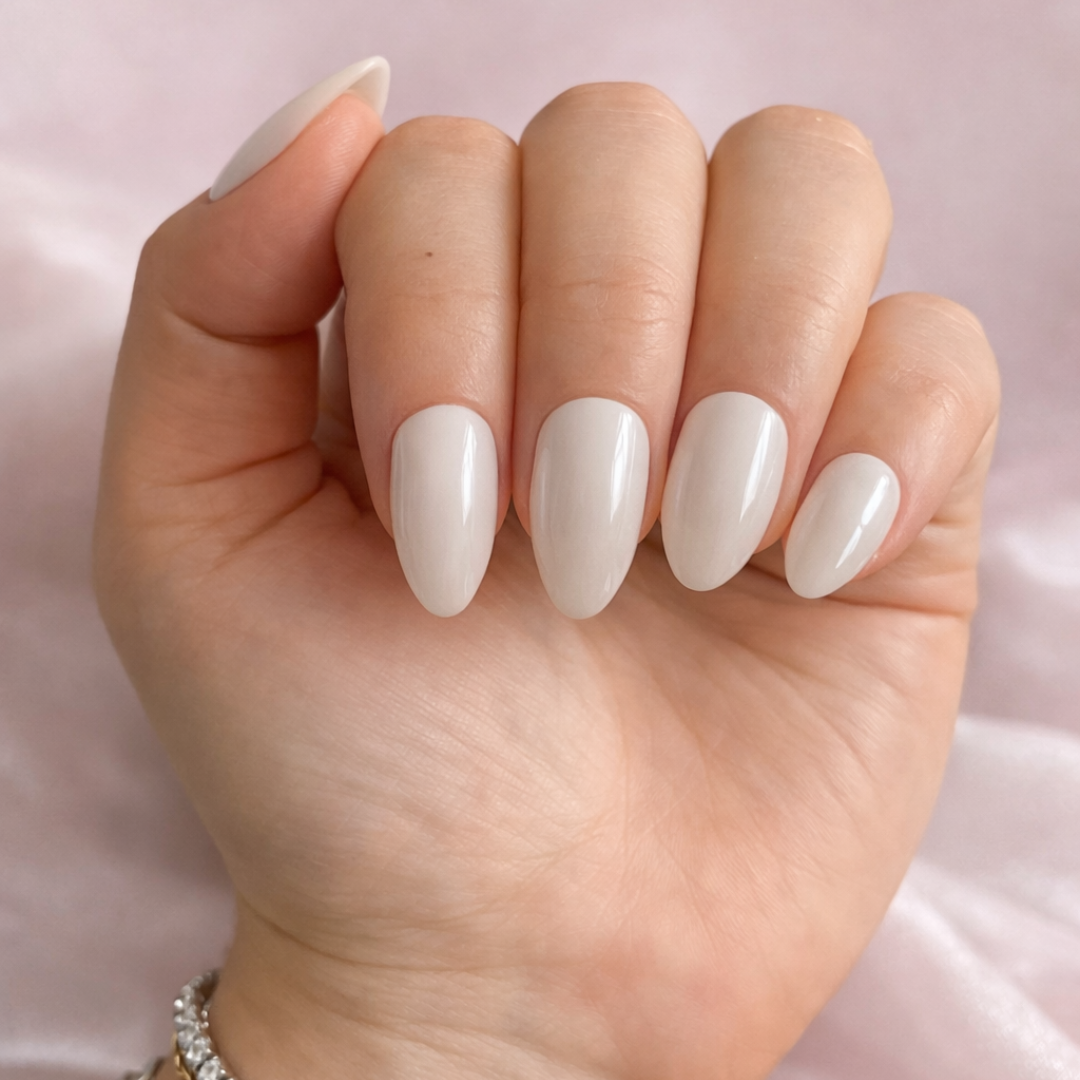 Hand with white nail polish on a light pink background